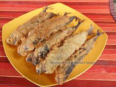 fried fish on a yellow plate sitting on a wooden table