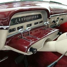 the interior of an old car with red and white leather upholstered seats, dash boards and dashboard controls