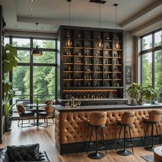 a bar with stools and tables in front of large windows overlooking the trees outside