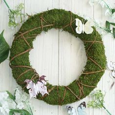 a moss wreath with white flowers and butterflies