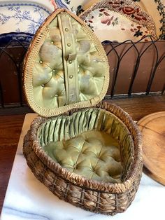 an empty wicker basket sitting on top of a white cloth covered table next to decorative plates