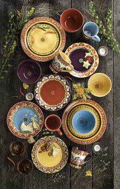 a table topped with lots of colorful plates and bowls on top of a wooden table