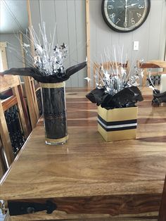 two vases filled with flowers on top of a wooden table next to a clock