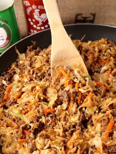 a skillet filled with meat and veggies next to two cans of soda