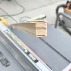 a piece of wood sitting on top of a metal tool belt next to a sawhorse