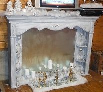 a white fireplace with candles and a television on top