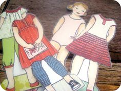 two children's paper dolls are standing next to each other on a wooden surface