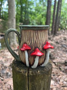 two mugs with mushrooms on them are sitting on a tree stump in the woods