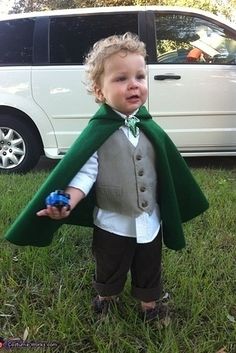 a little boy dressed up in a green cape