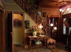 an ornate entry way with stairs and table in the center, surrounded by wooden paneling