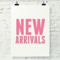 a white and pink poster with the words new arrivals on it against a brick wall