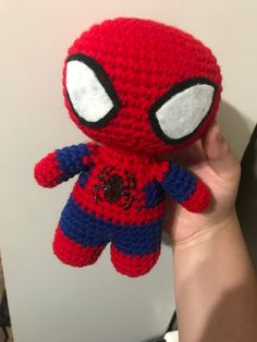 a hand holding a crocheted spiderman stuffed animal with big eyes and an eye patch