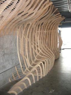 a large piece of art made out of wicker on display in a room with concrete walls