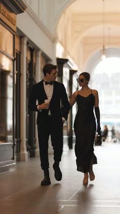 a man and woman walking down the street in front of an entrance to a building