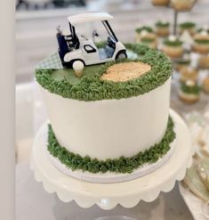 a golf themed cake on a table with cupcakes and desserts in the background