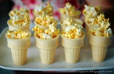 small cones filled with popcorn sitting on top of a white plate