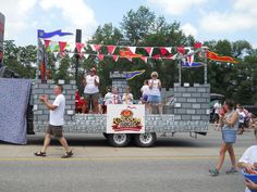 some people are standing on the back of a truck in front of a brick wall