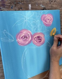 a person is painting flowers on a canvas