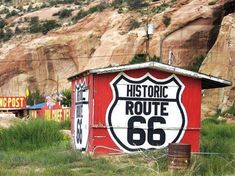 an old route 66 sign is painted on the side of a building in front of a mountain