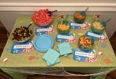 a green table topped with lots of food and desserts next to a bowl of fruit