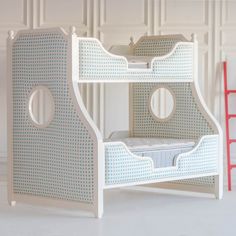 a white and blue doll house bed with two beds on each side in front of a red chair