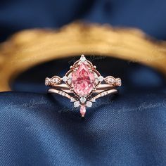 a pink diamond ring sitting on top of a blue cloth