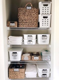 the closet is organized with baskets, laundry and other items in white bins on shelves