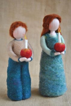 two miniature dolls holding apples and candles