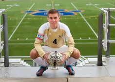 a young man holding a soccer ball sitting on top of a bleacherside