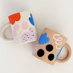 two coffee mugs sitting next to each other on top of a white countertop