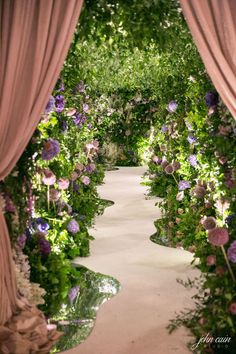 an archway covered in flowers and greenery with pink drapes over it's sides