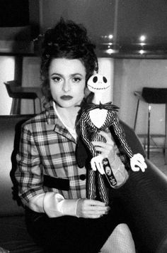 a black and white photo of a woman holding a stuffed toy doll in her hand