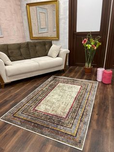 a living room filled with furniture and a rug on top of a hard wood floor