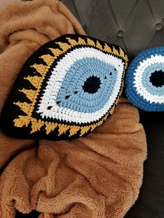 two crocheted pillows with an evil eye on them are laying next to each other