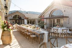 an outdoor dining area with tables, chairs and flowers on the table in front of it