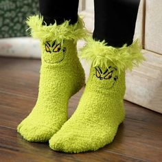 the legs and feet of a person wearing fuzzy yellow socks with eyes drawn on them