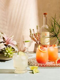 two glasses filled with orange juice and garnished with limes on a table