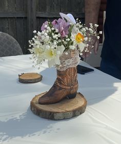 a cowboy boot with flowers in it sitting on a table