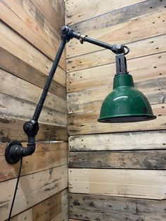 a green light hanging from the side of a wooden wall next to a lamp fixture