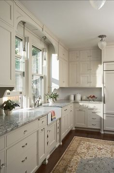 a large kitchen with white cabinets and marble counter tops, along with an area rug on the floor