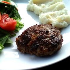 a white plate topped with meat and veggies next to mashed potato wedges