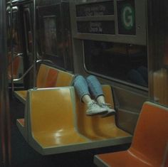 a person sitting on a subway train with their feet up and legs crossed, while the other end is empty