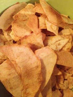 a green bowl filled with potato chips on top of a table