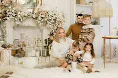 a family posing for a photo in front of a fireplace with christmas decorations on the mantle