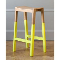 a yellow wooden stool sitting on top of a hard wood floor next to a wall