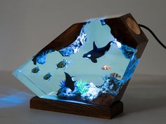 an aquarium with fish and other marine life in it's display case on a wooden stand