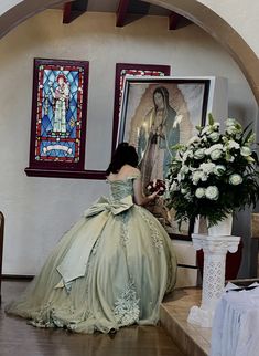 a woman in a ball gown sitting on the floor next to a vase with flowers