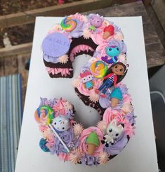 there is a birthday cake made to look like the number 5 with cupcakes on it