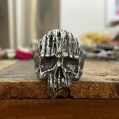 a silver skull ring sitting on top of a wooden table