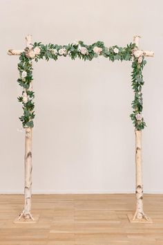 a wooden cross decorated with flowers and greenery on top of a hard wood floor